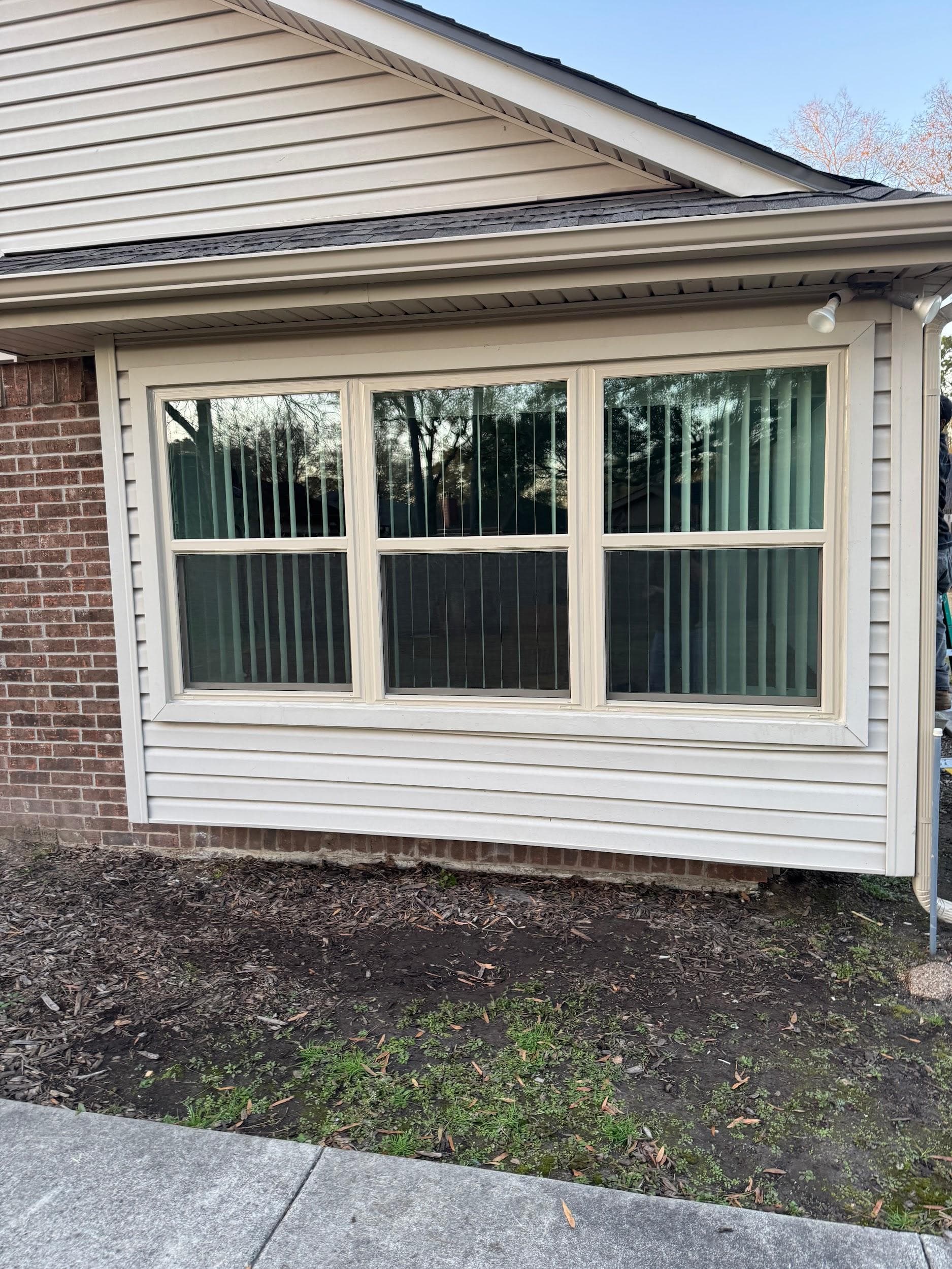 A three-wide almond-framed single-hung window unit on tan siding