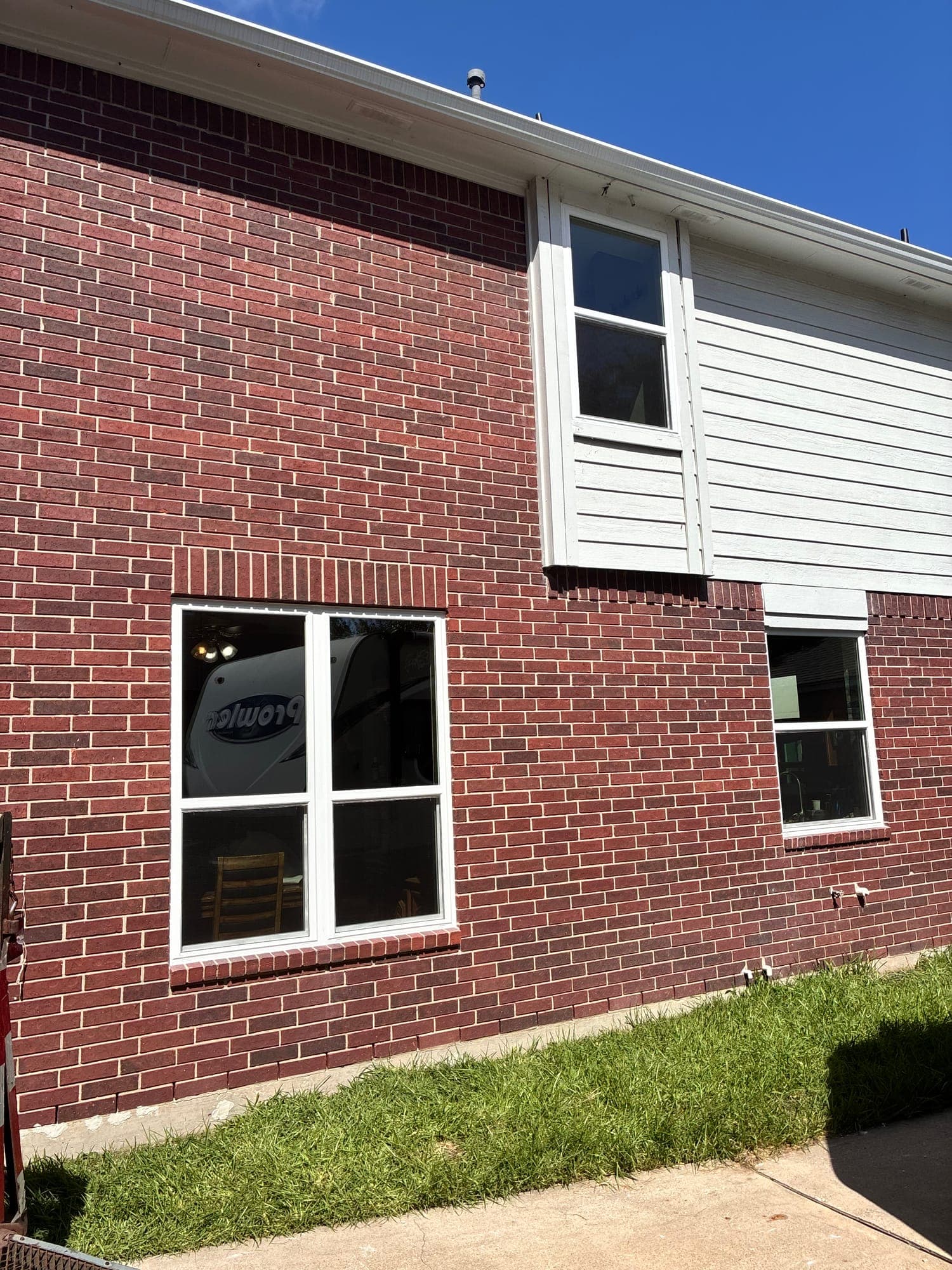 White single-hung windows on a dark red-brick side elevation
