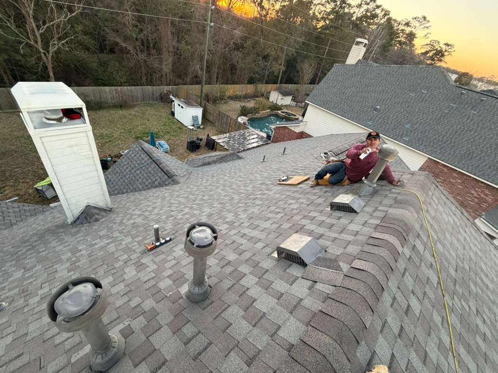 Crew finishing near the chimney chase on a completed roof at sunset