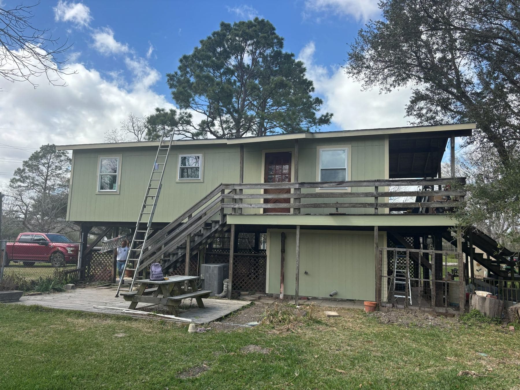 After: the stilted house re-sided in sage-green James Hardie siding with cream trim