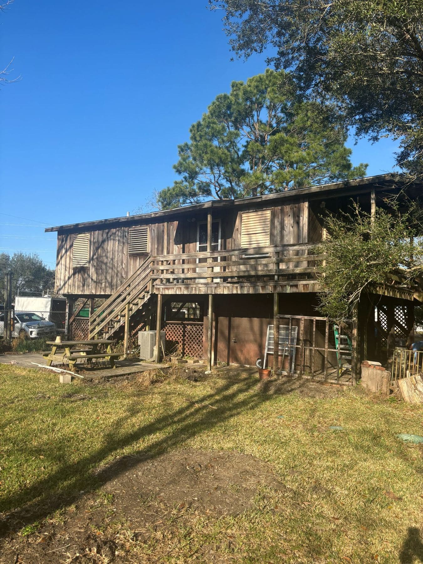 Before: weathered dark board siding on a stilted coastal house