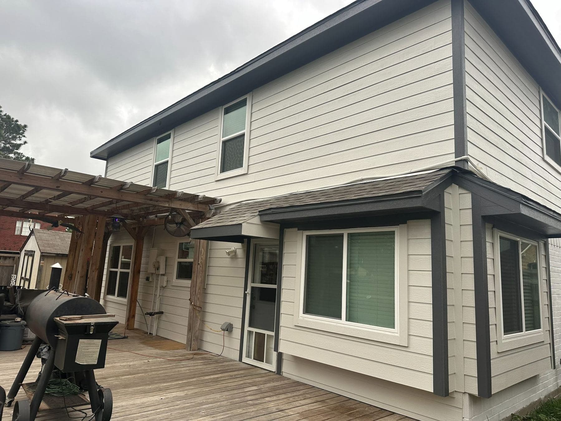 Back deck of the white two-story with new Hardie lap siding and charcoal fascia