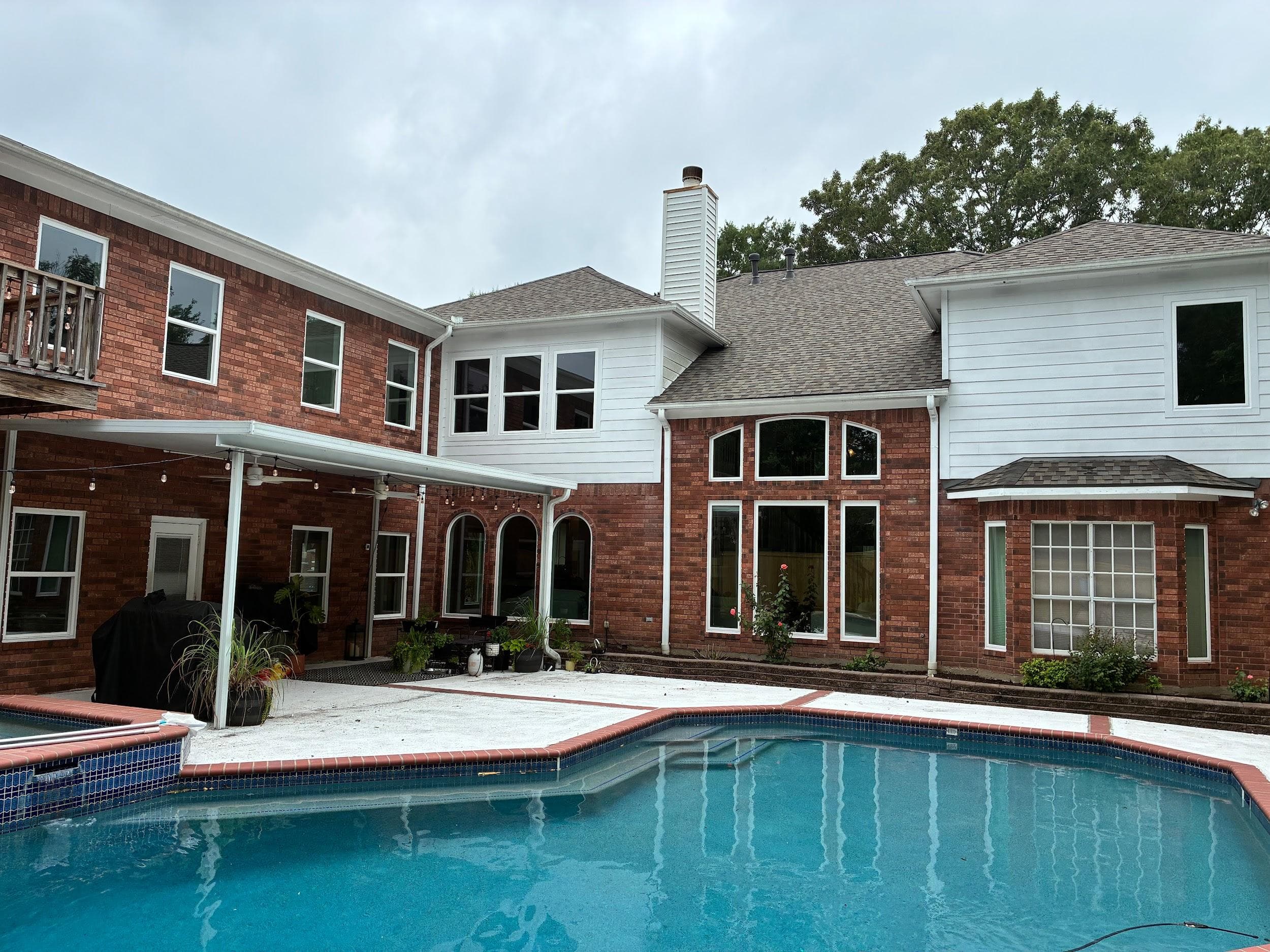 White picture windows overlooking a backyard pool
